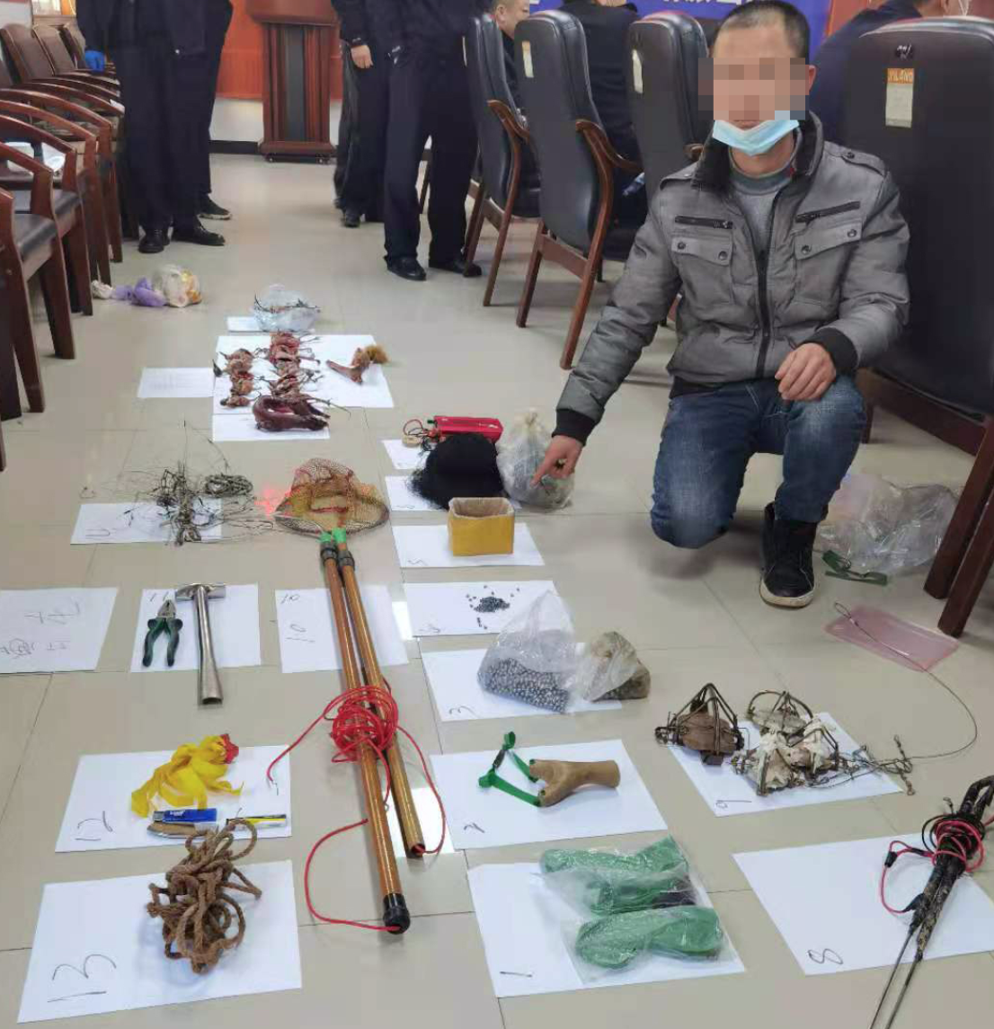(犯罪嫌疑人现场指认猎捕的野生动物和作案工具。 通讯员 摄)